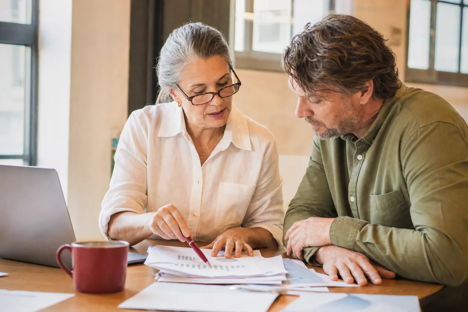 An accountant reviewing printed reports with a business owner at a table