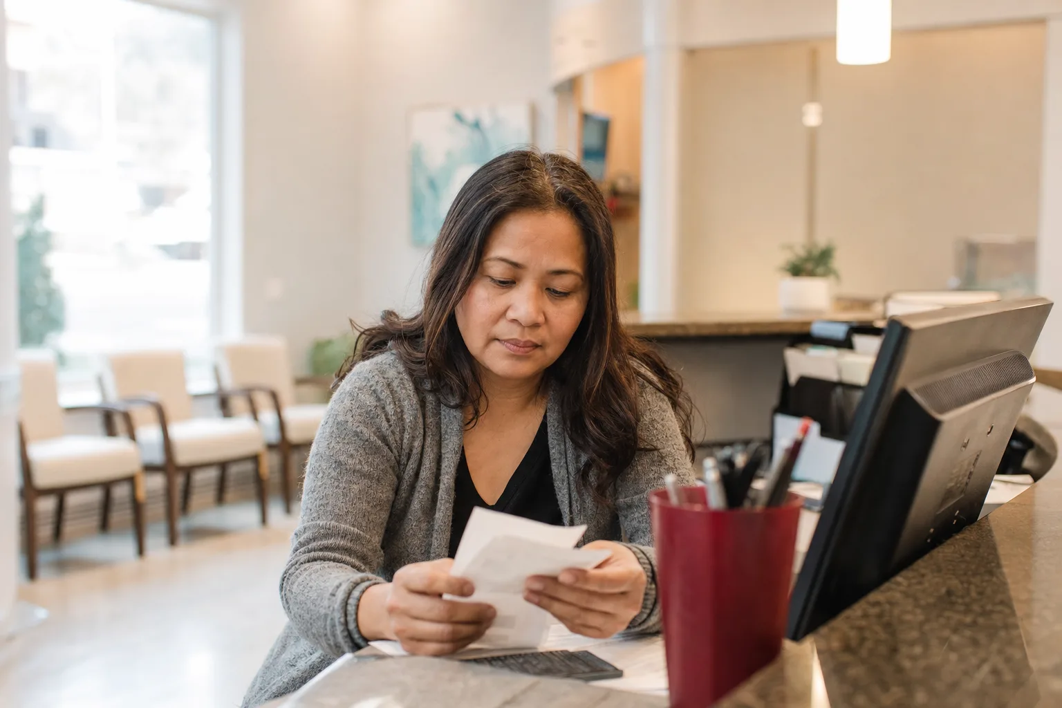 A dental clinic office manager at the front desk going over the day's payments